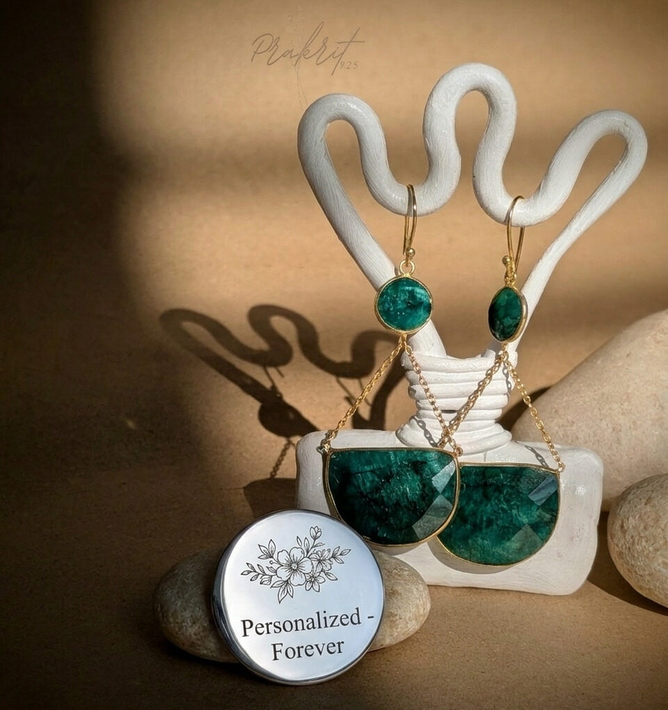 Emerald green stone gold-plated dangle earrings with geometric design, displayed on artistic stand, personalized jewelry concept